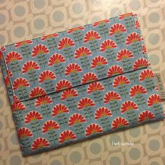 an envelope is sitting on top of a patterned tablecloth with red and blue flowers