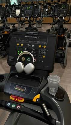 there are many treadmills in the gym with headphones on them and water