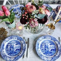 a blue and white table setting with flowers in a vase