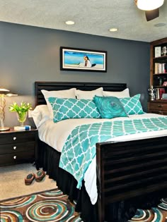 a bedroom with blue and white bedding, green accents and a chair in front of the bed