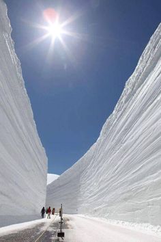 the sun shines brightly over people walking down a snow - covered road on a sunny day