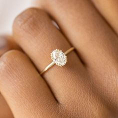 a woman's hand with a diamond ring on her left hand, showing the center stone