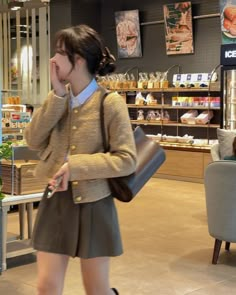 a woman walking through a store while talking on a cell phone and holding a purse