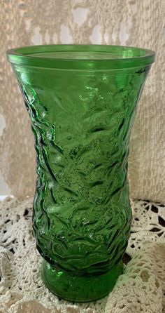 a green glass vase sitting on top of a doily