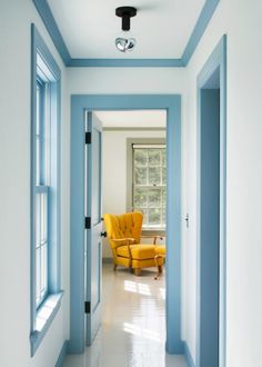 an instagram photo of a blue and white hallway with a yellow chair in the middle