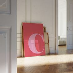 an empty room with white walls and wooden flooring has a pink poster on the wall