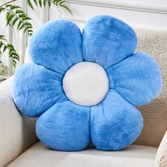 a blue flower shaped pillow sitting on top of a couch