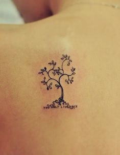 a small tree tattoo on the back of a woman's shoulder