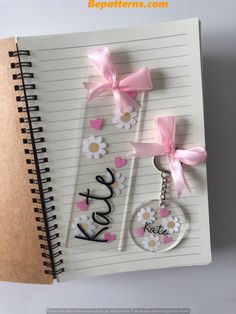 an open notebook with two keychains attached to it and flowers on the cover