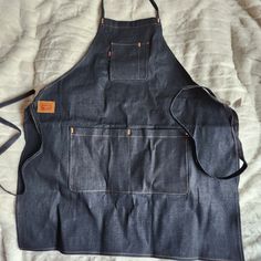 an apron made out of blue jeans on top of a white sheet with a brown tag