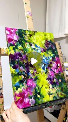 someone is painting flowers on an easel