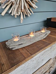 three candles are lit on a driftwood tray