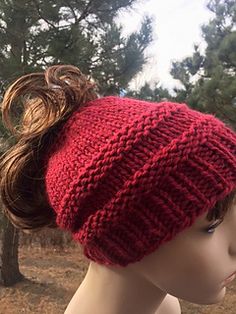 a female mannequin head wearing a red knitted hat with a messy ponytail