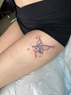 a woman's thigh with a small fairy tattoo on her left leg and stars in the background