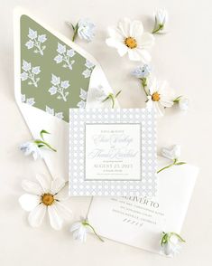 the wedding stationery is laid out on top of each other with daisies and flowers