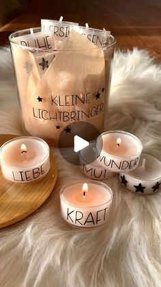 five lit candles sitting on top of a white fur covered floor next to a bag