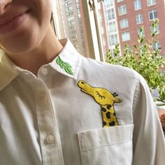 a close up of a person wearing a shirt with a giraffe embroidered on it