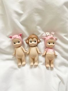 three little dolls sitting next to each other on a white sheet