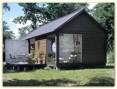 a small wooden cabin sitting on top of a lush green field