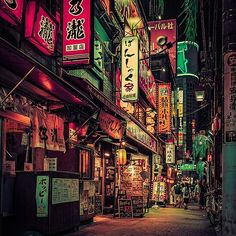 an alley way with neon signs on the buildings and trees in the city at night