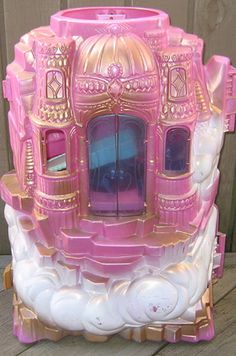 a pink and white toy castle sitting on top of a wooden floor