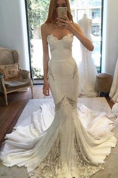 a woman taking a selfie while wearing a wedding dress in front of a mirror