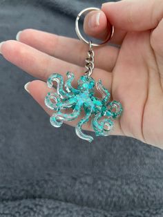 a person is holding an octopus keychain in their hand