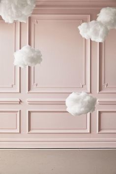 there are clouds hanging from the ceiling in this pink room with white walls and wood flooring