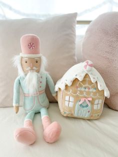 two stuffed toys sitting on top of a bed next to pillows and a pillow with a gingerbread house