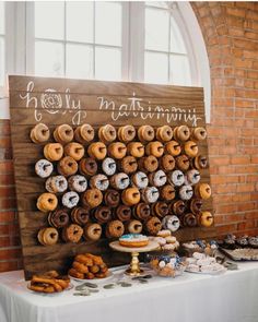 a table topped with lots of donuts next to a sign