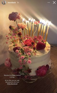 a birthday cake with candles and flowers on it