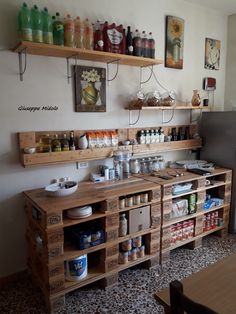 a kitchen filled with lots of wooden shelves and food on top of each shelf in front of a refrigerator