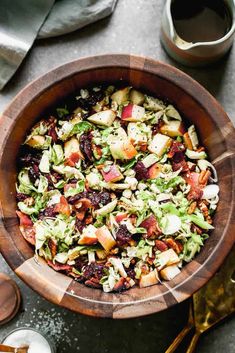 a wooden bowl filled with salad next to silverware