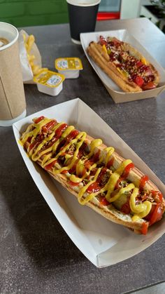 two hotdogs with condiments sit on a table