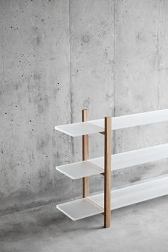 a white shelf with three shelves on each side in front of a concrete wall and cement floor