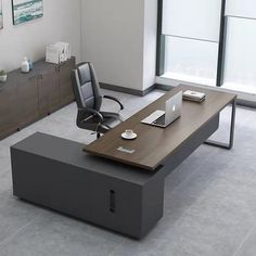 an office desk with a laptop on it in the middle of a large open room