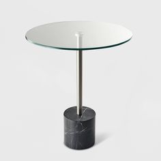 a round glass table with a metal base and black marble base, on a white background