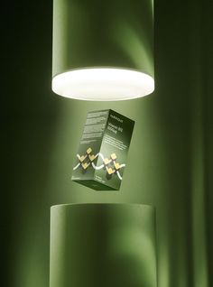 a green lamp hanging from the side of a wall next to a book on top of a table