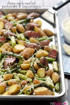 potatoes and asparagus on a baking sheet with parmesan sprinkles