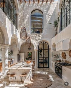 an indoor kitchen and dining area with white walls, arched doorways, and stone flooring