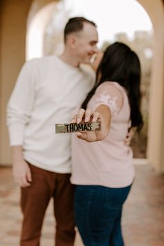 a man and woman standing next to each other holding up a piece of paper that says thomas