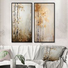 two paintings hanging on the wall above a white couch in a living room with a coffee table