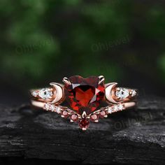 a red heart shaped ring sitting on top of a piece of wood with diamonds around it