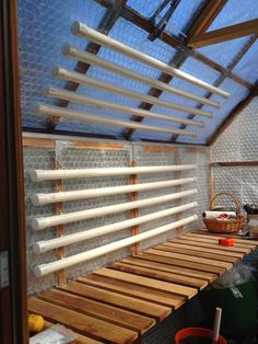 the inside of a greenhouse with wooden slats and plastic tubes hanging from the ceiling