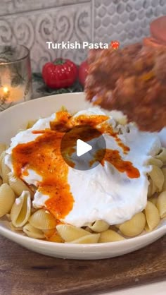 a bowl filled with pasta and sauce on top of a wooden table