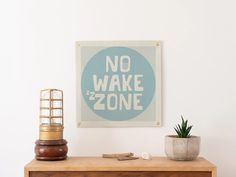 there is a sign that says no wake zone next to a potted plant on a dresser