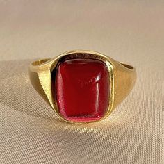 Antique 18k yellow gold ring from the United Kingdom. This signet ring features a vibrant synthetic ruby cabochon. Great antique condition Size: 7.5 resizable* Weight: 3.5 grams Band: 11.1 mm (front), 1.7 mm (back) Synth Ruby: 8.3 mm x 10.0 mm Hallmarks:18CT Formal Gold Cabochon Signet Ring, Formal Ruby Signet Ring, Heirloom Red Signet Ring With Polished Finish, Classic Yellow Gold Signet Ring With Cabochon, Modern Gold Signet Ring With Cabochon, Formal Ruby Signet Ring In Fine Jewelry Style, Fine Jewelry Ruby Signet Ring For Formal Occasions, Ruby Signet Ring Fine Jewelry For Formal Events, Formal Ruby Signet Ring With Bezel Setting