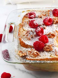 raspberry french toast with powdered sugar and walnuts in a glass casserole dish