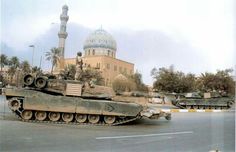 two tanks are parked in front of a building with a dome on it's roof