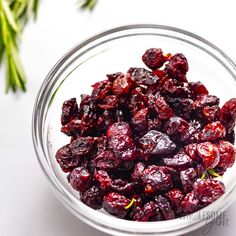 a glass bowl filled with dried cranberries on top of a table